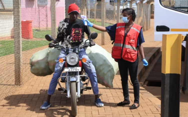 Um profissional de saúde queniano verifica a temperatura de viajantes que cruzam a fronteira de Uganda para o Quênia. — Foto: Andrew Kasuku/AP